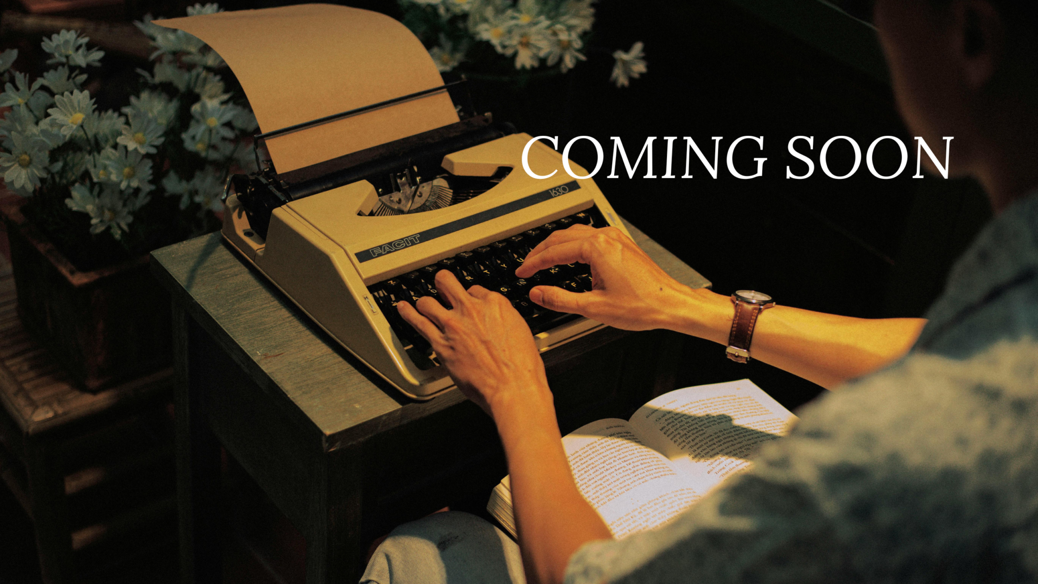 A writer at a vintage typewriter, working on a manuscript surrounded by flowers